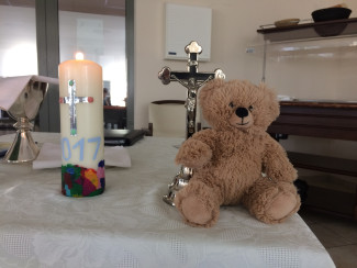 Ein Altar mit Kreuz, brennender Kerze und Teddybär